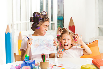 Image showing The young mother and her little daughter drawing with pencils at home