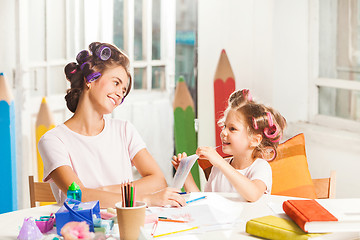 Image showing The young mother and her little daughter drawing with pencils at home