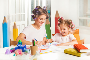 Image showing The young mother and her little daughter drawing with pencils at home