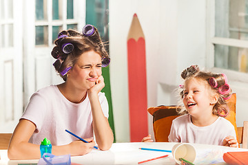 Image showing The young mother and her little daughter drawing with pencils at home