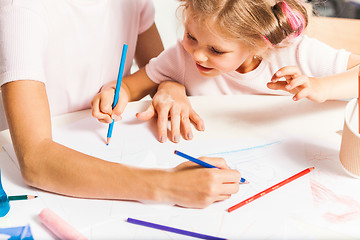 Image showing The young mother and her little daughter drawing with pencils at home