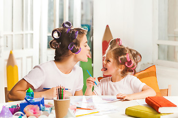 Image showing The young mother and her little daughter drawing with pencils at home