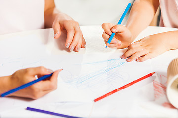 Image showing The young mother and her little daughter drawing with pencils at home