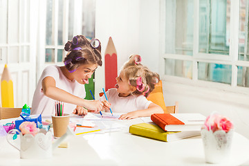 Image showing The young mother and her little daughter drawing with pencils at home