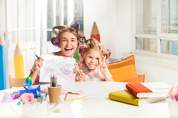 Image showing The young mother and her little daughter drawing with pencils at home