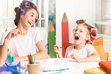 Image showing The young mother and her little daughter drawing with pencils at home