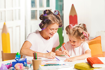 Image showing The young mother and her little daughter drawing with pencils at home