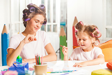 Image showing The young mother and her little daughter drawing with pencils at home