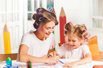 Image showing The young mother and her little daughter drawing with pencils at home