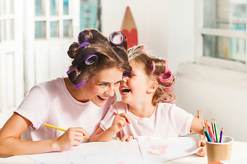 Image showing The young mother and her little daughter drawing with pencils at home