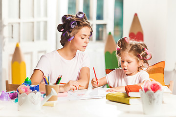 Image showing The young mother and her little daughter drawing with pencils at home