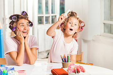 Image showing The young mother and her little daughter drawing with pencils at home