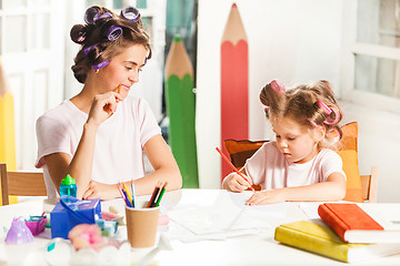Image showing The young mother and her little daughter drawing with pencils at home