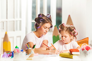 Image showing The young mother and her little daughter drawing with pencils at home