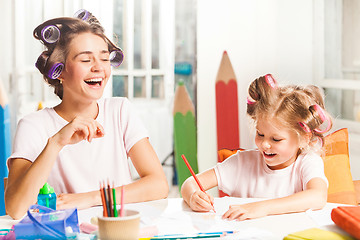 Image showing The young mother and her little daughter drawing with pencils at home