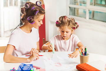 Image showing The young mother and her little daughter drawing with pencils at home