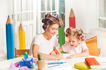 Image showing The young mother and her little daughter drawing with pencils at home