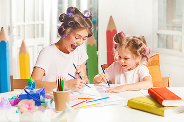 Image showing The young mother and her little daughter drawing with pencils at home