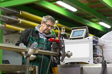 Image showing Industrial worker setting orbital welding machine.