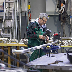 Image showing Industrial worker setting orbital welding machine.