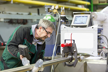 Image showing Industrial worker setting orbital welding machine.