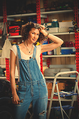 Image showing beautiful woman in blue overalls in the interior of the garage