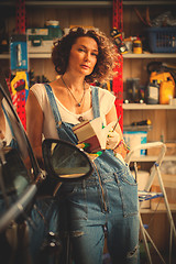 Image showing adorable woman car mechanic in blue overalls with a book-instruc