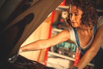 Image showing beautiful auto mechanic woman near the car with open the bonnet