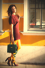 Image showing smiling middle-aged woman in a burgundy dress and handbag