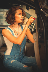 Image showing mechanic woman in a blue overalls repair with a screwdriver the 