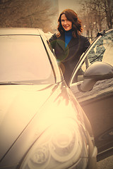 Image showing smiling woman in a dark coat opened the car door