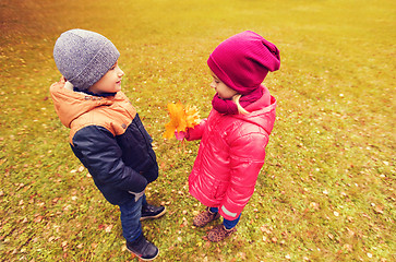 Image showing little boy giving autumn maple leaves to girl