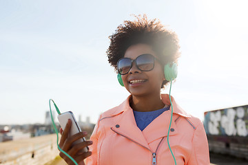 Image showing happy young woman with smartphone and headphones