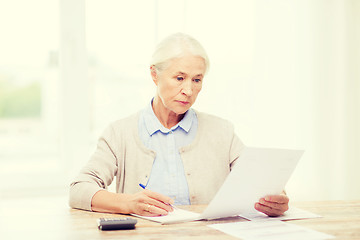 Image showing senior woman with papers and calculator at home