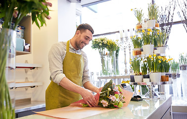 Image showing florist wrapping flowers in paper at flower shop