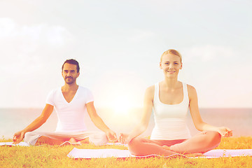 Image showing smiling couple making yoga exercises outdoors