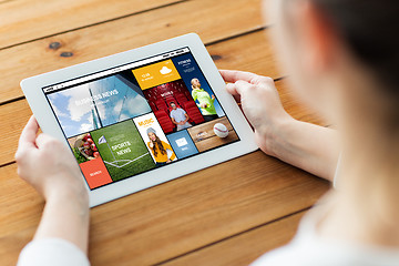 Image showing close up of woman with tablet pc on wooden table