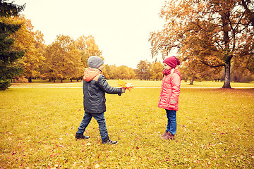 Image showing little boy giving autumn maple leaves to girl
