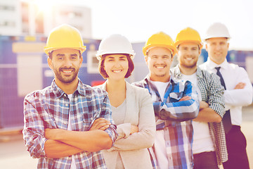 Image showing group of smiling builders in hardhats outdoors