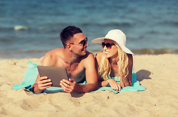 Image showing happy couple with tablet pc sunbathing on beach