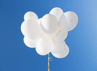 Image showing close up of white helium balloons in blue sky