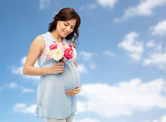 Image showing happy pregnant woman with flowers touching belly