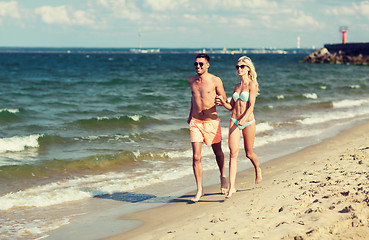 Image showing happy couple in swimwear running on summer beach