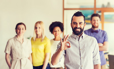 Image showing happy young man over creative team in office