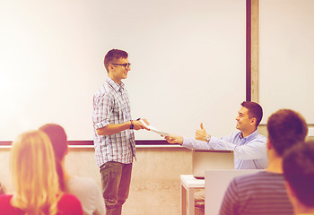 Image showing group of students and smiling teacher with notepad