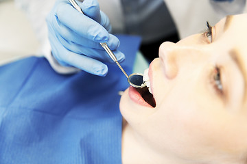 Image showing close up of dentist examining female patient teeth