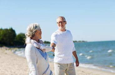 Image showing happy senior couple holding hands on summer beach