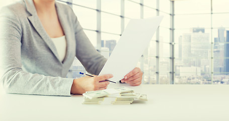 Image showing close up of female hands with money and tax report