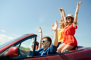 Image showing happy friends driving in cabriolet car at country