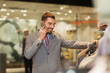 Image showing happy man calling on smartphone at clothing store